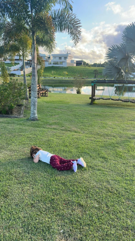 Criança deitada na grama, em um parque
